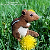 Chipmunk sitting on the lawn with dandelions.